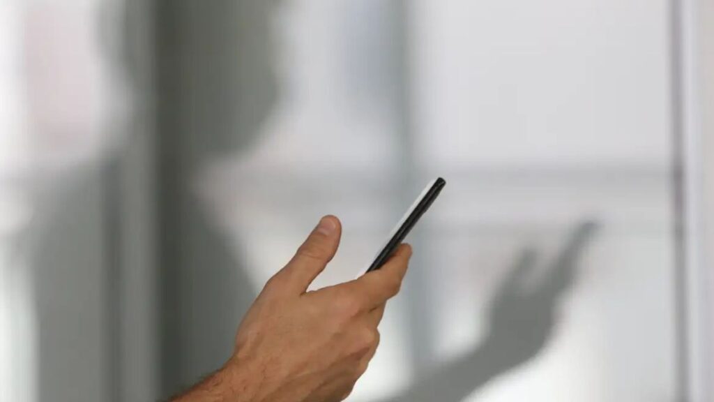 Imagem colorida de pessoa segurando o celular