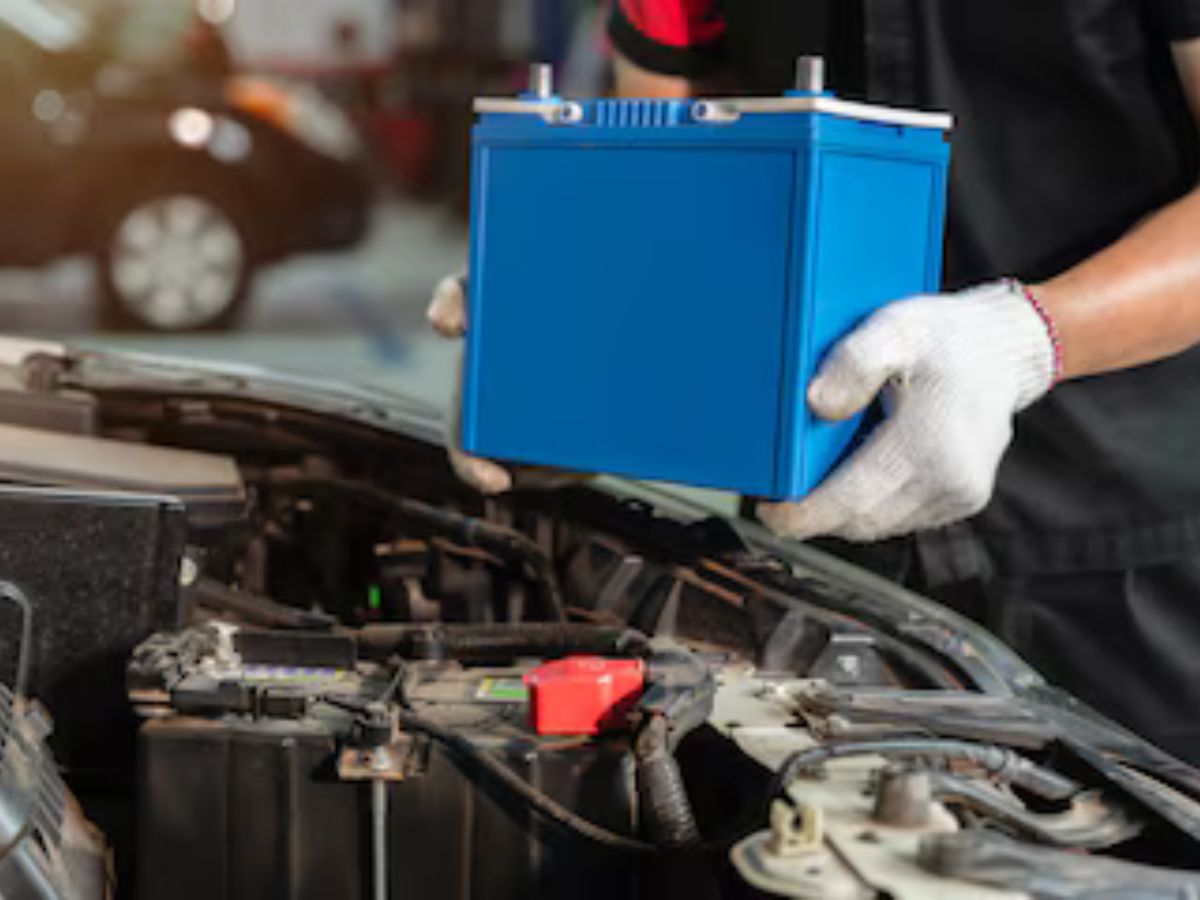 Homem tirando uma bateria de carro do vaículo