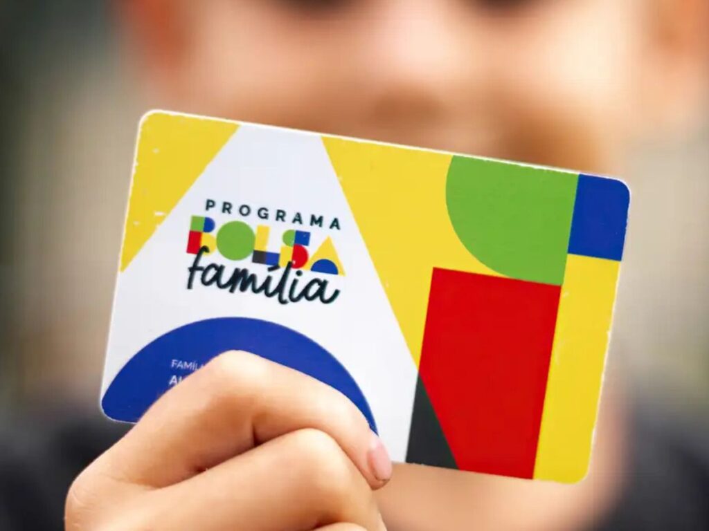 A imagem mostra uma criança segurando o cartão do bolsa família