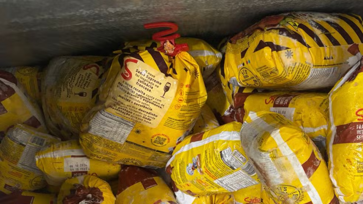 ALIMENTOS VENCIDOS Diversos frangos congelados da marca Sadia embalados em sacos amarelos, empilhados dentro de um freezer industrial.