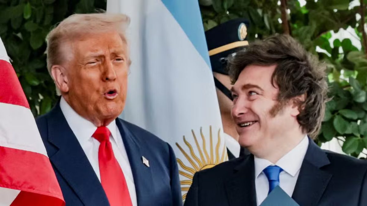 Milei e Trump Trump e Milei lado a lado, conversando, com as bandeiras da Argentina e Estados Unidos ao fundo