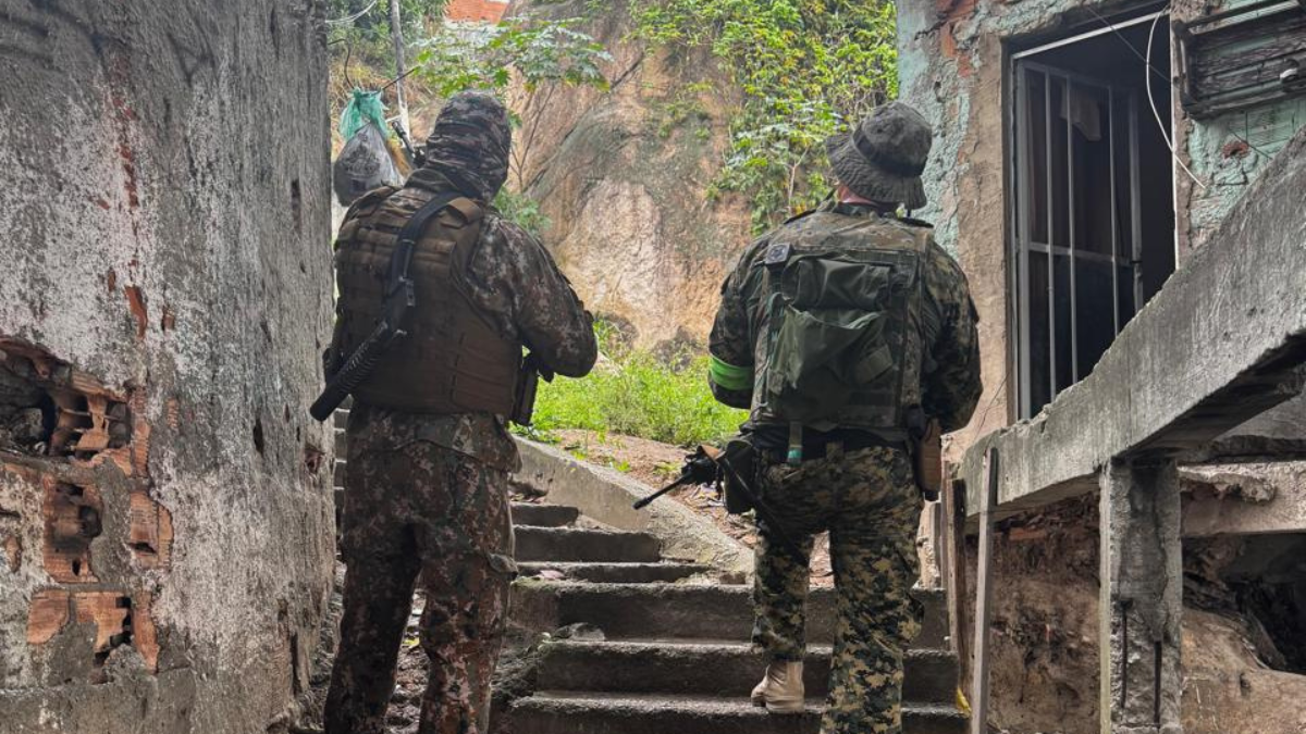 Megaoperação Rio Policiais militares de costas, subindo uma escada, em uma comunidade.
