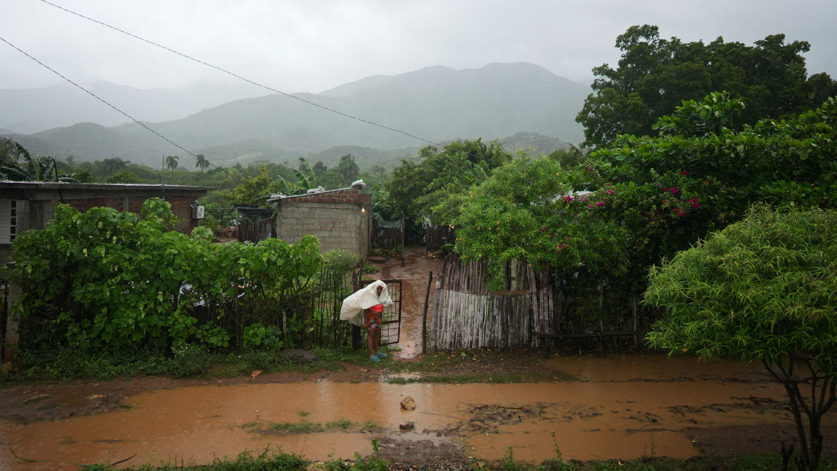 Melissa Mulher tenta se proteger do furacão em frente a uma rua alagada