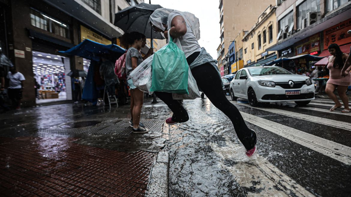Chuva Homem pula sobre uma poça d'água ao atravessar a rua na faixa de pedestres