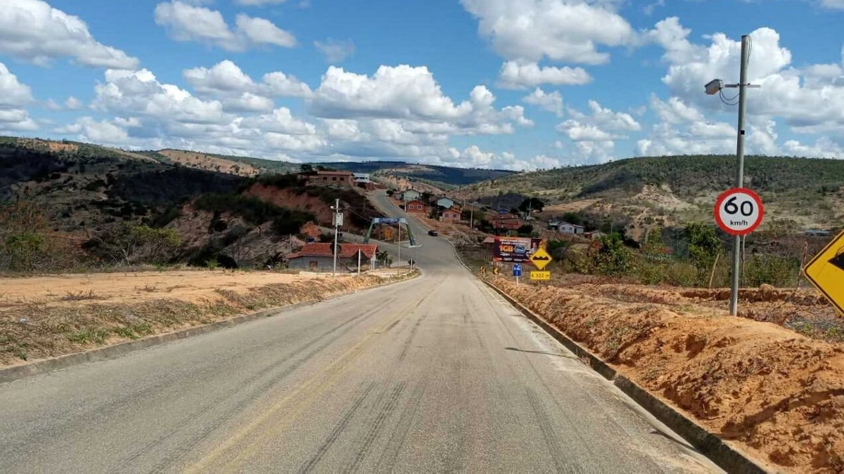 Estrada Minas Radar de controle de velocidade instalado em rodovia de área rural, próximo a vegetação e montes, em um dia ensolarado.