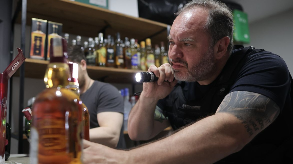 homem analisa garrafa de bebida adulterada
