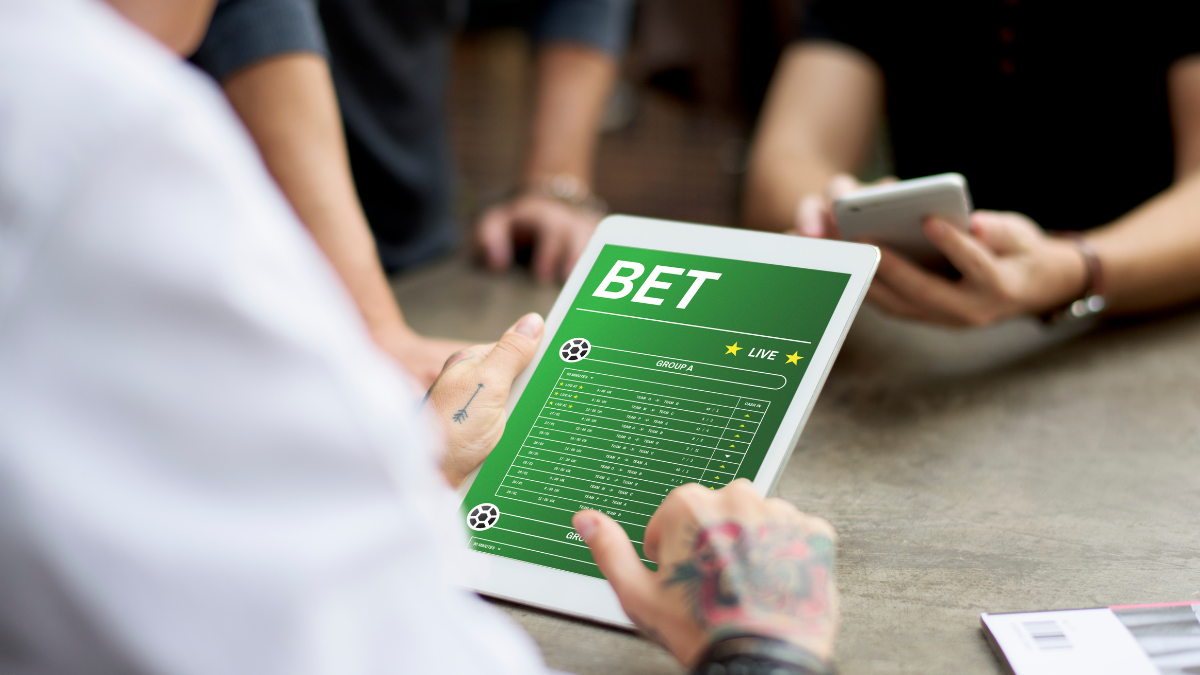 Close na mão de uma pessoa navegando em uma página de bet, em um tablete