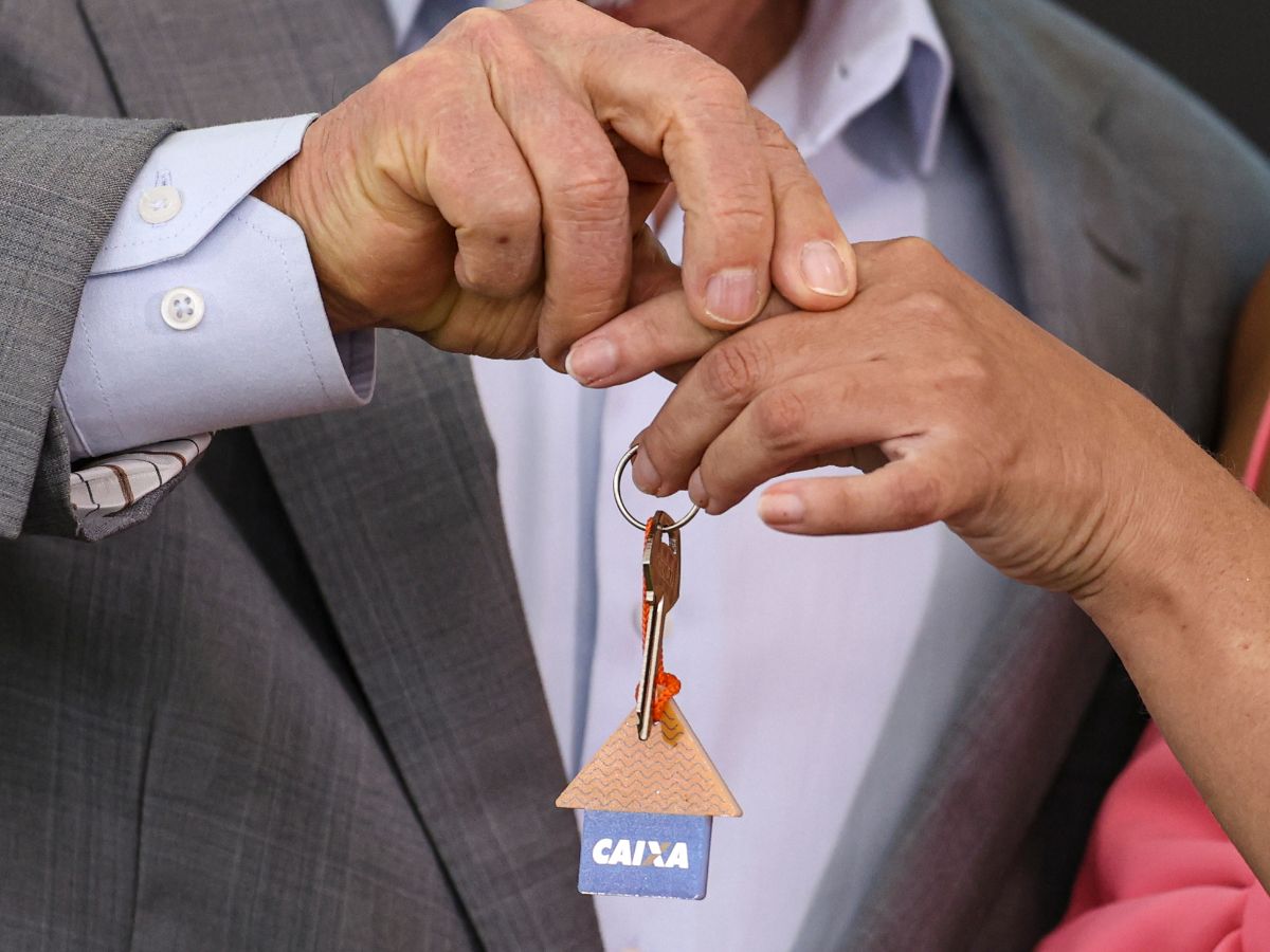 casa-caixa Pessoas segurando uma chave com logotipo da Caixa Econômica Federal
