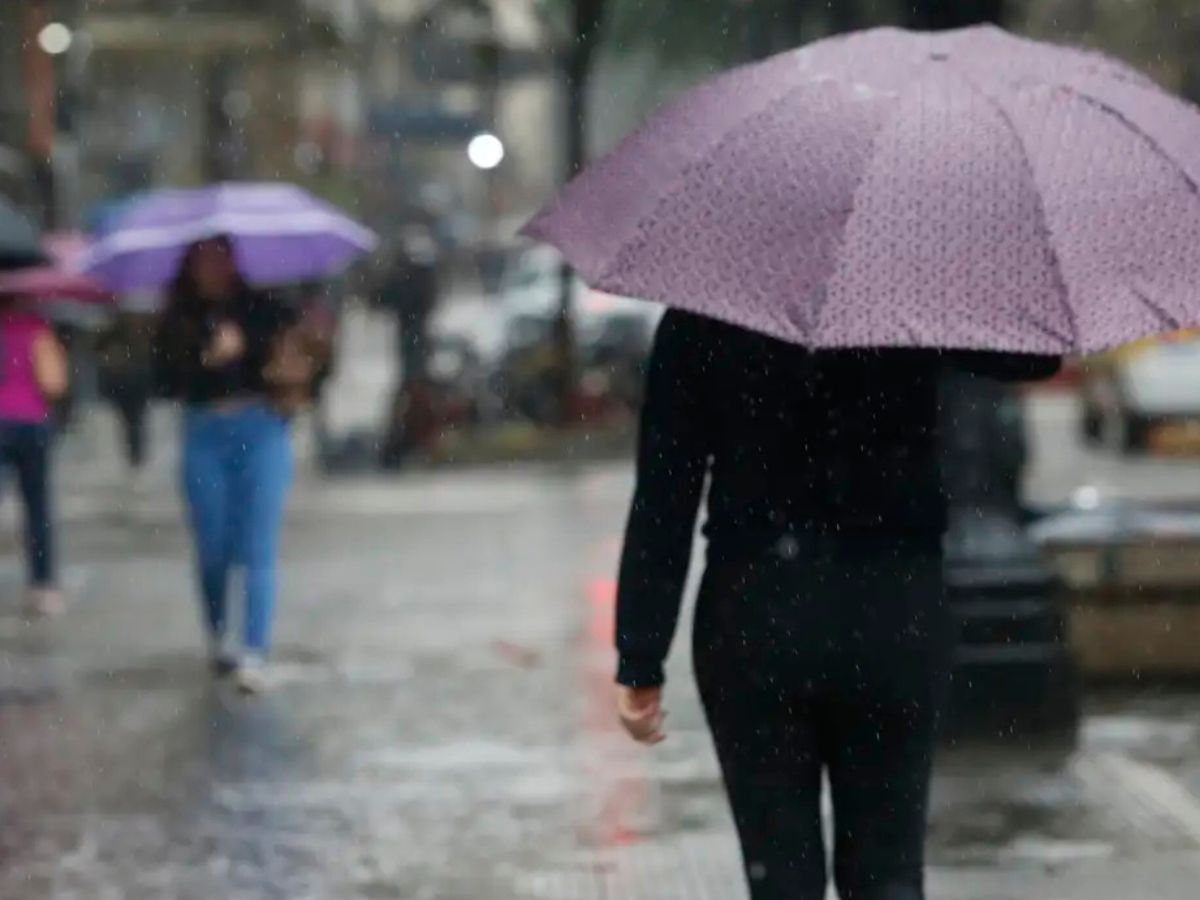 Pessoas andando na rua com guarda-chuva durante temporal