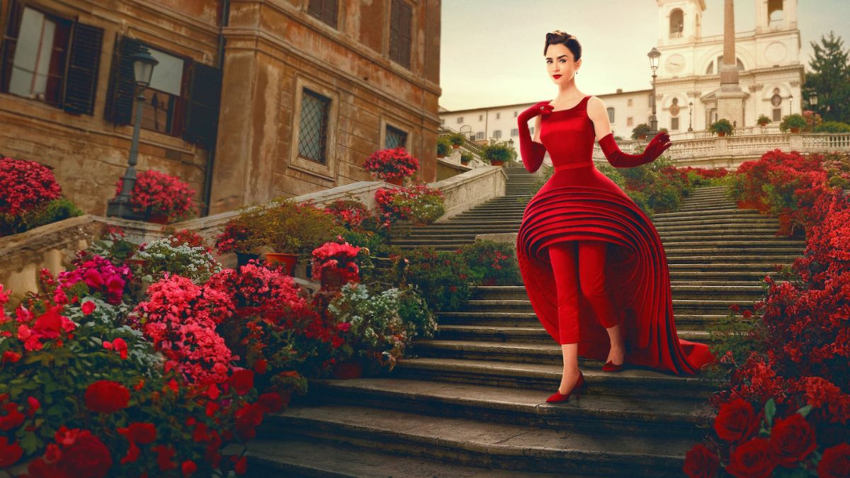 emily-em-paris-ganha-teaser-temporada Protagonista Lilly Collins de Emily Em Paris , descendo uma escada de vestido vermelho