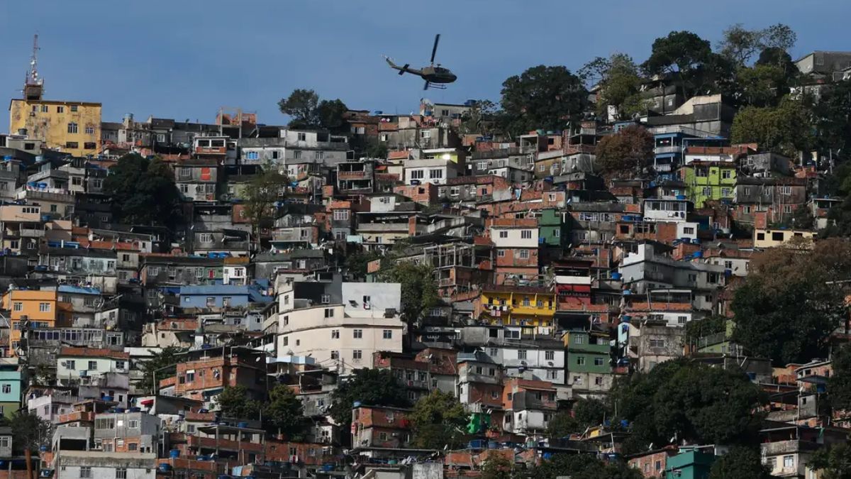 favela rio Fernando Frazão Agência Brasil Uma foto panorâmica, tirada em plano aberto, que mostra uma grande favela ou comunidade verticalizada no Rio de Janeiro, estendendo-se por um morro. A cena é capturada em um dia claro, com céu azul.