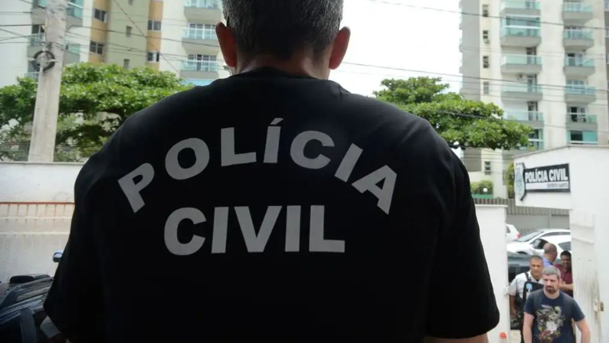 polícia civil rj Imagem de um policial de costas com uma camisa preta. Na vestimenta, está escrito