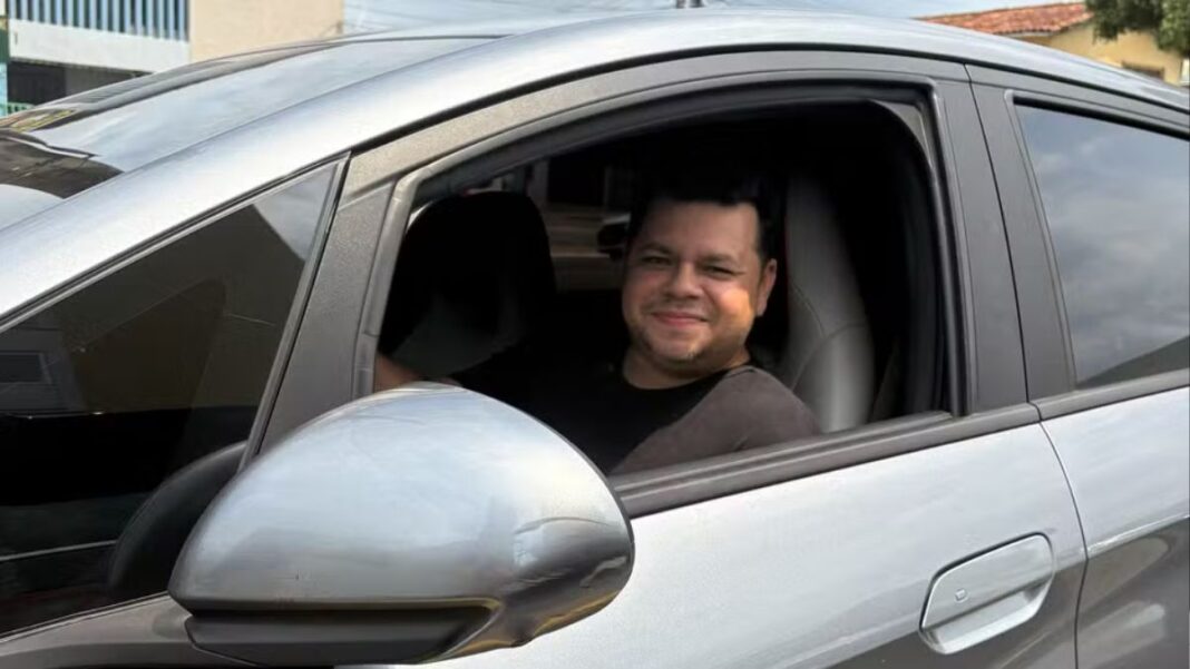 Motorista Alberto dentro de um carro prata, no banco do motorista