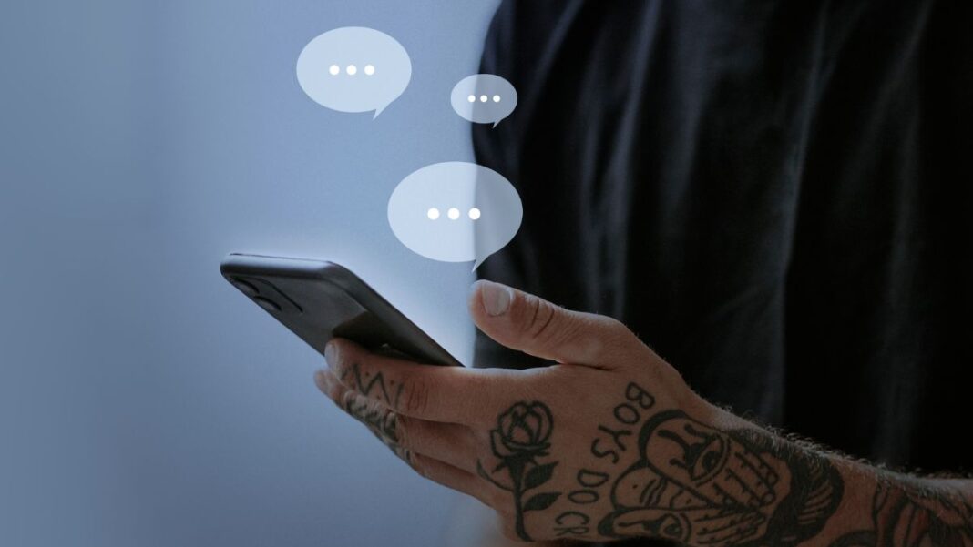 Homem segurando smartphone; balões transparentes contendo três pontinhos saem da tela