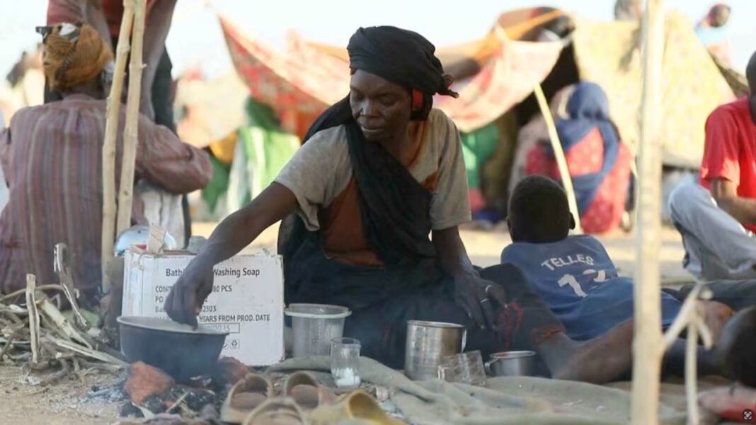 Uma mulher sudanesa deslocada prepara chá enquanto outras pessoas se reúnem e sentam em tendas improvisadas após fugirem da cidade de Al-Fashir, em Darfur, em Tawila, Sudão, em 29 de outubro de 2025