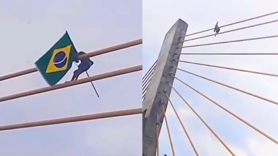Imagem mostra um homem fincando uma bandeira do Brasil no alto de uma ponte estaiada, entre o Maranhão e Piauí