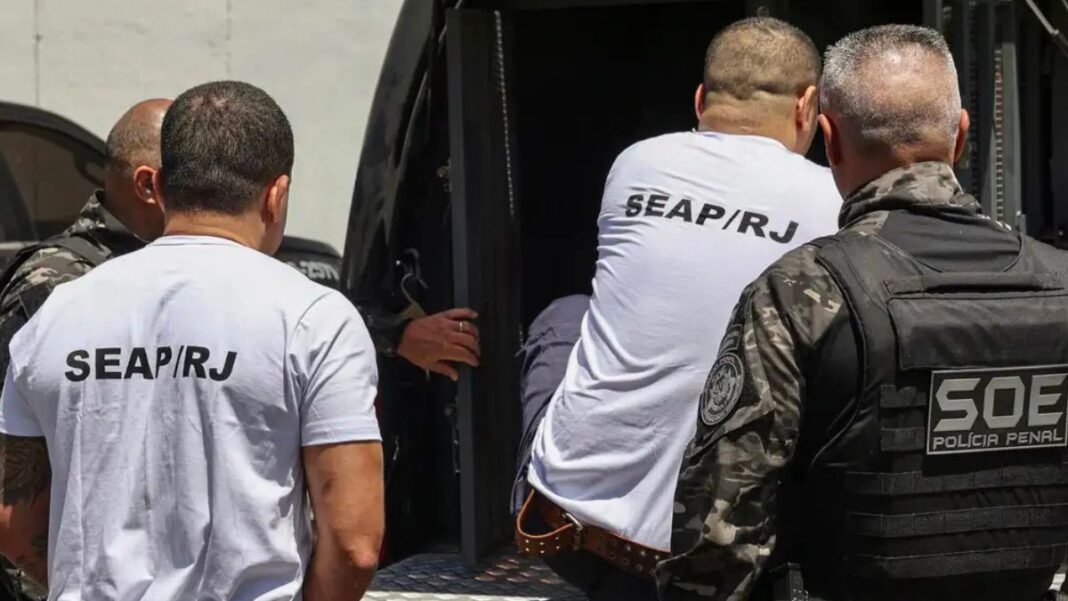 homens entrando em veículo policial para serem transferidos