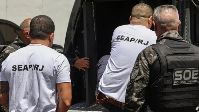 homens entrando em veículo policial para serem transferidos